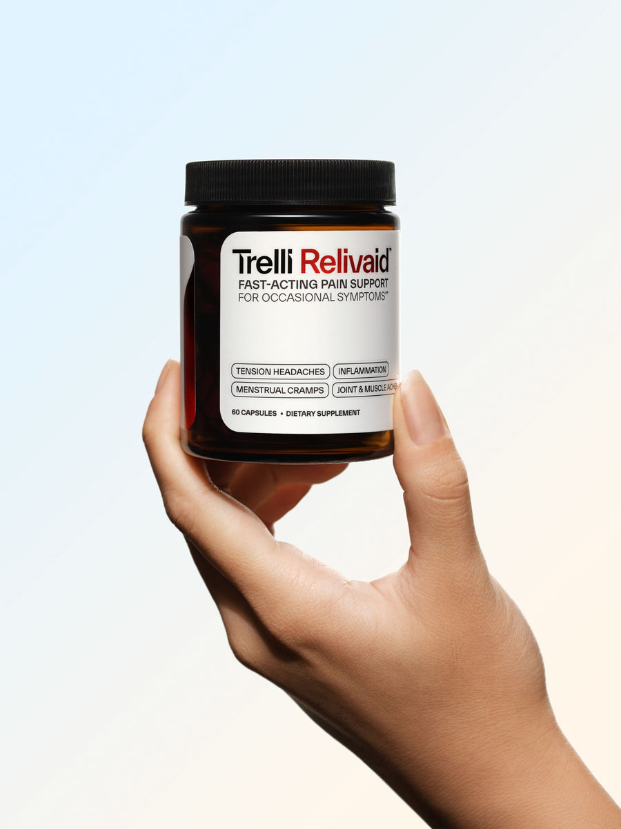 A hand holding up a jar of Trelli Relivaid, label facing the camera
